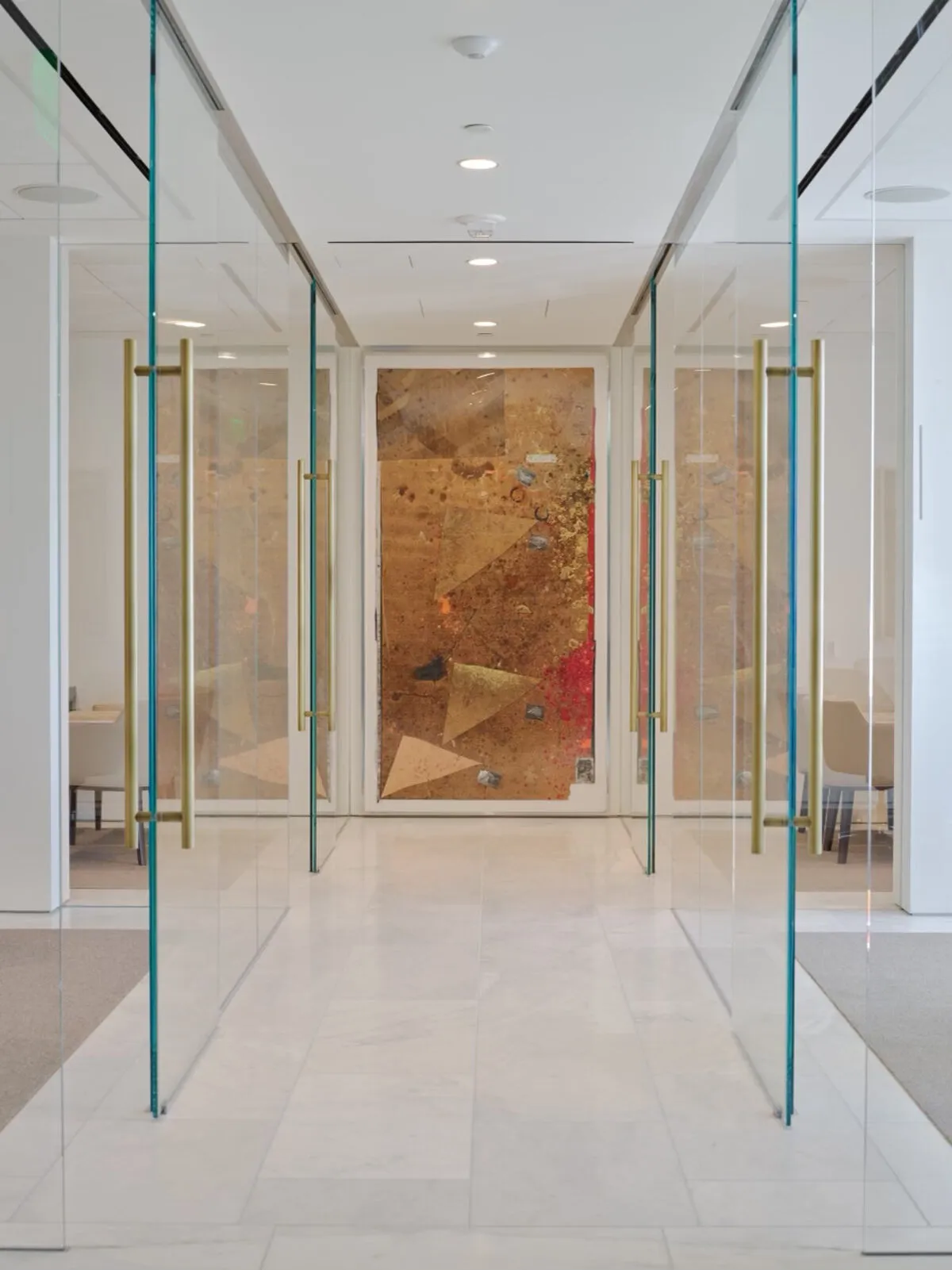 Large gold and red mixed-media artwork at the end of a corridor framed by glass doors with brass handles