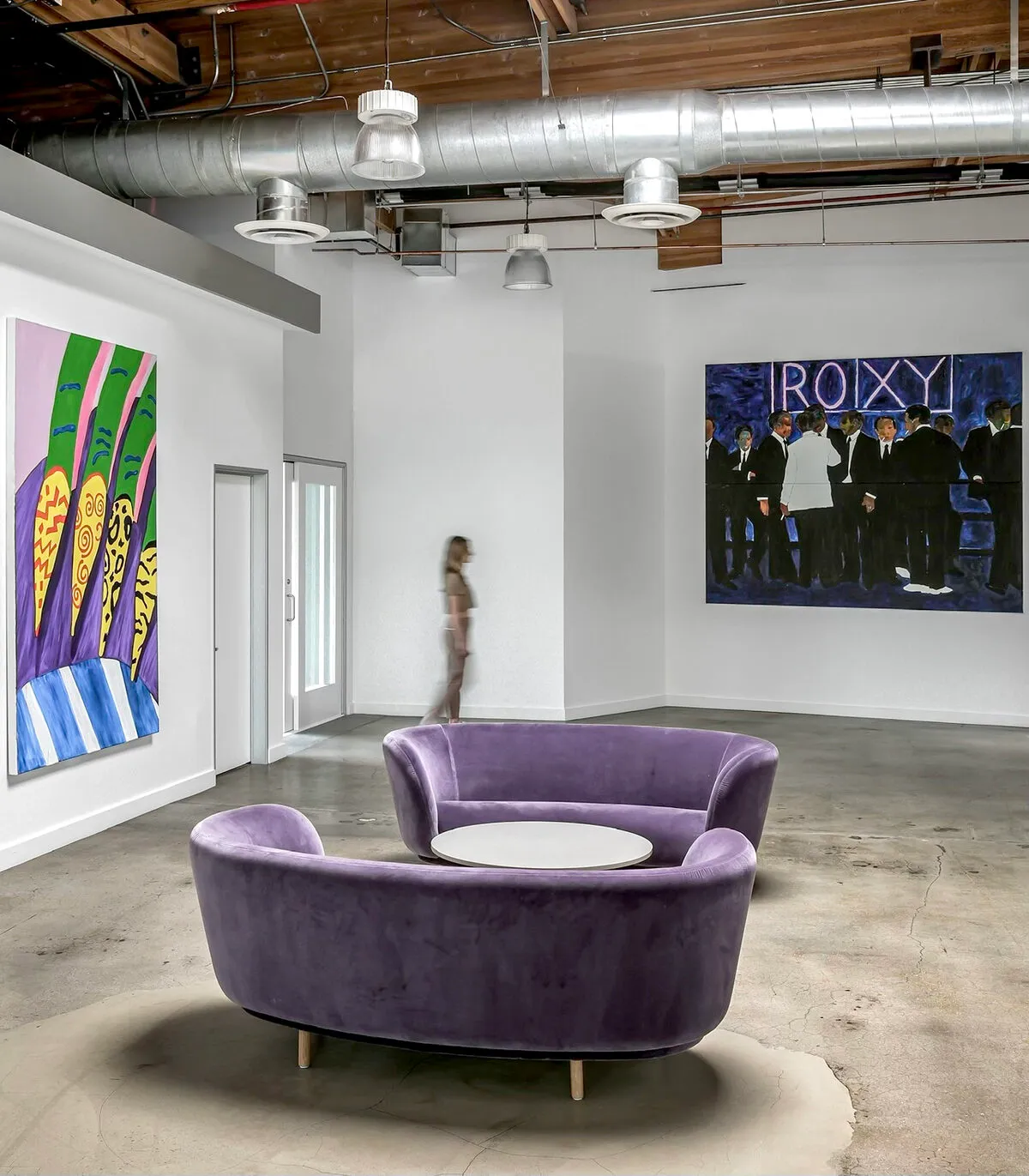 Office lounge with purple velvet sofas, a bold green and purple painting and a large painting of a crowd