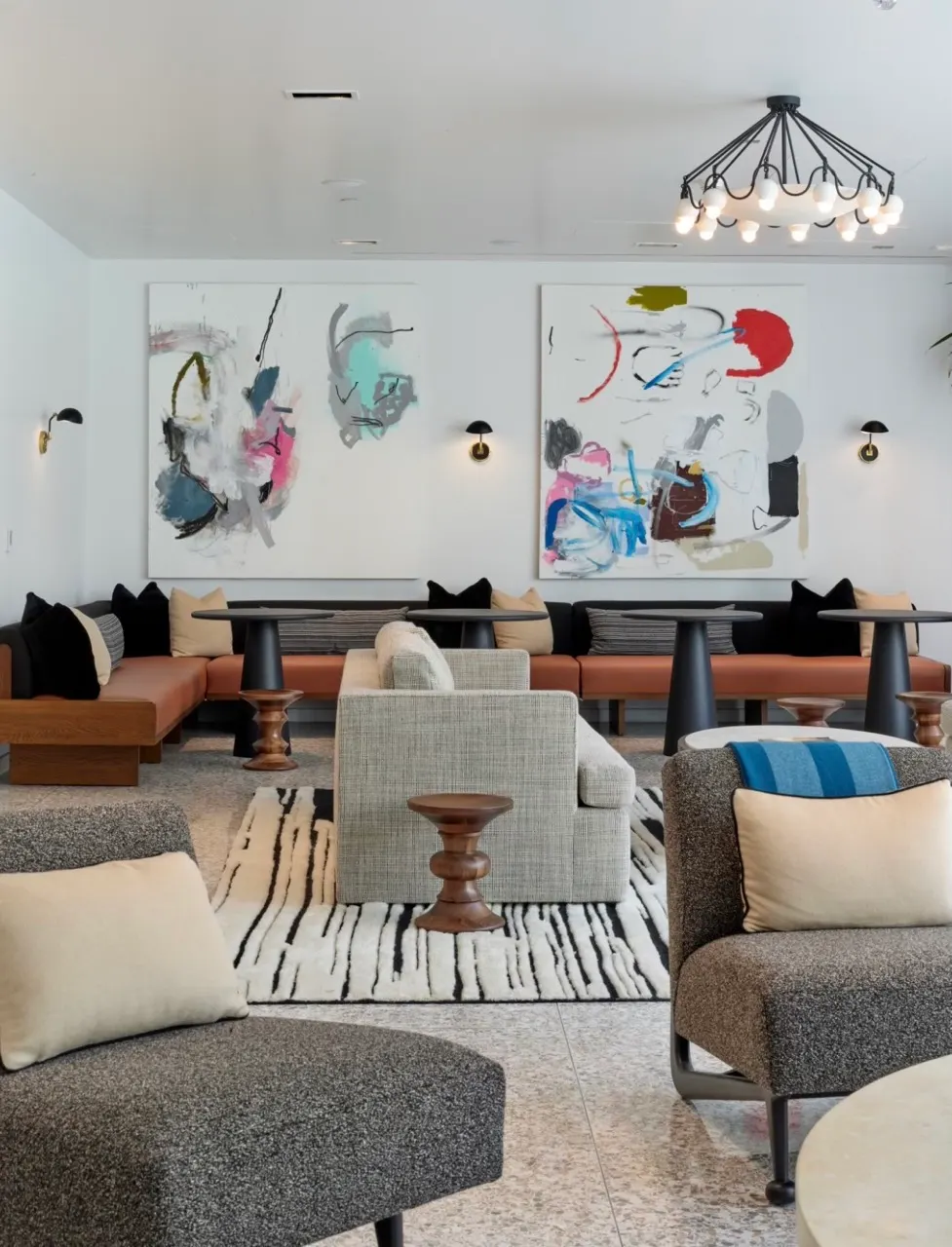Two large abstract paintings with pink, blue and red gestures above banquette seating in a lounge