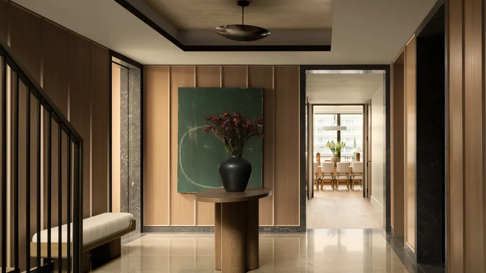 Wood-paneled entry hall with a round pedestal table, dark vase and a large green abstract painting