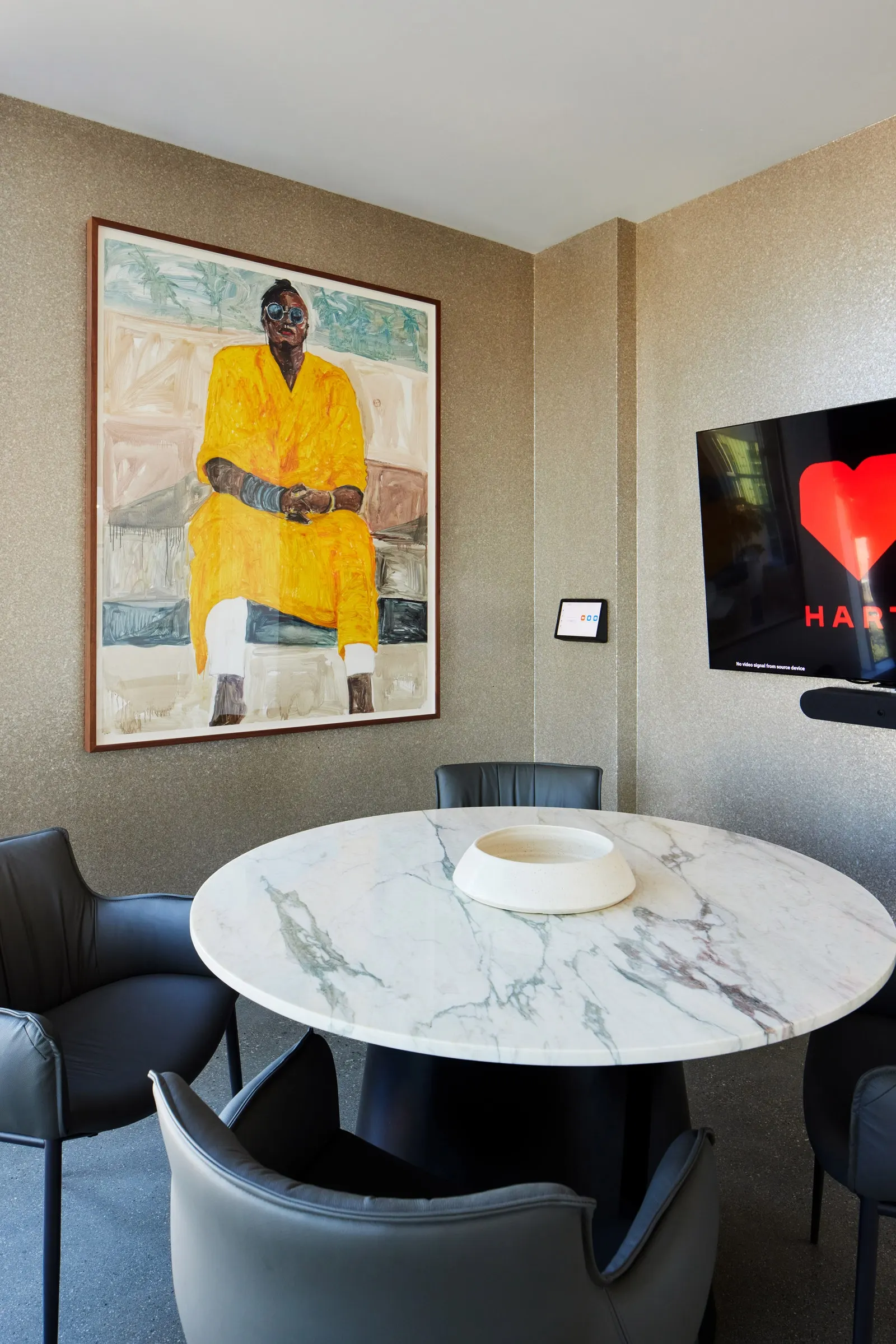 Large painted portrait of a seated man in a yellow robe above a round marble table in a meeting room