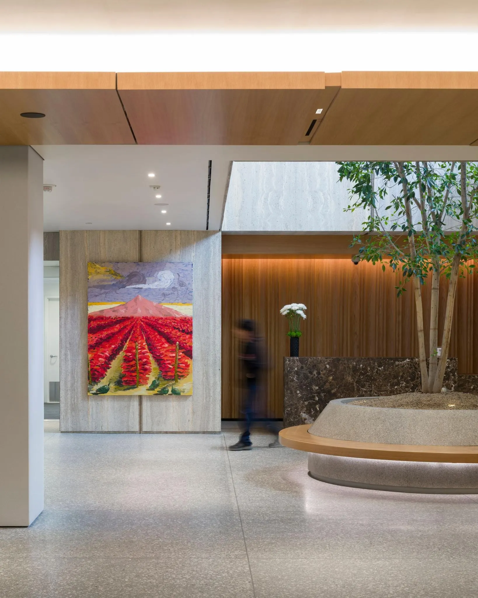 Painting of red flower fields below a pink mountain in an office lobby, artwork by Ken Taylor Reynaga
