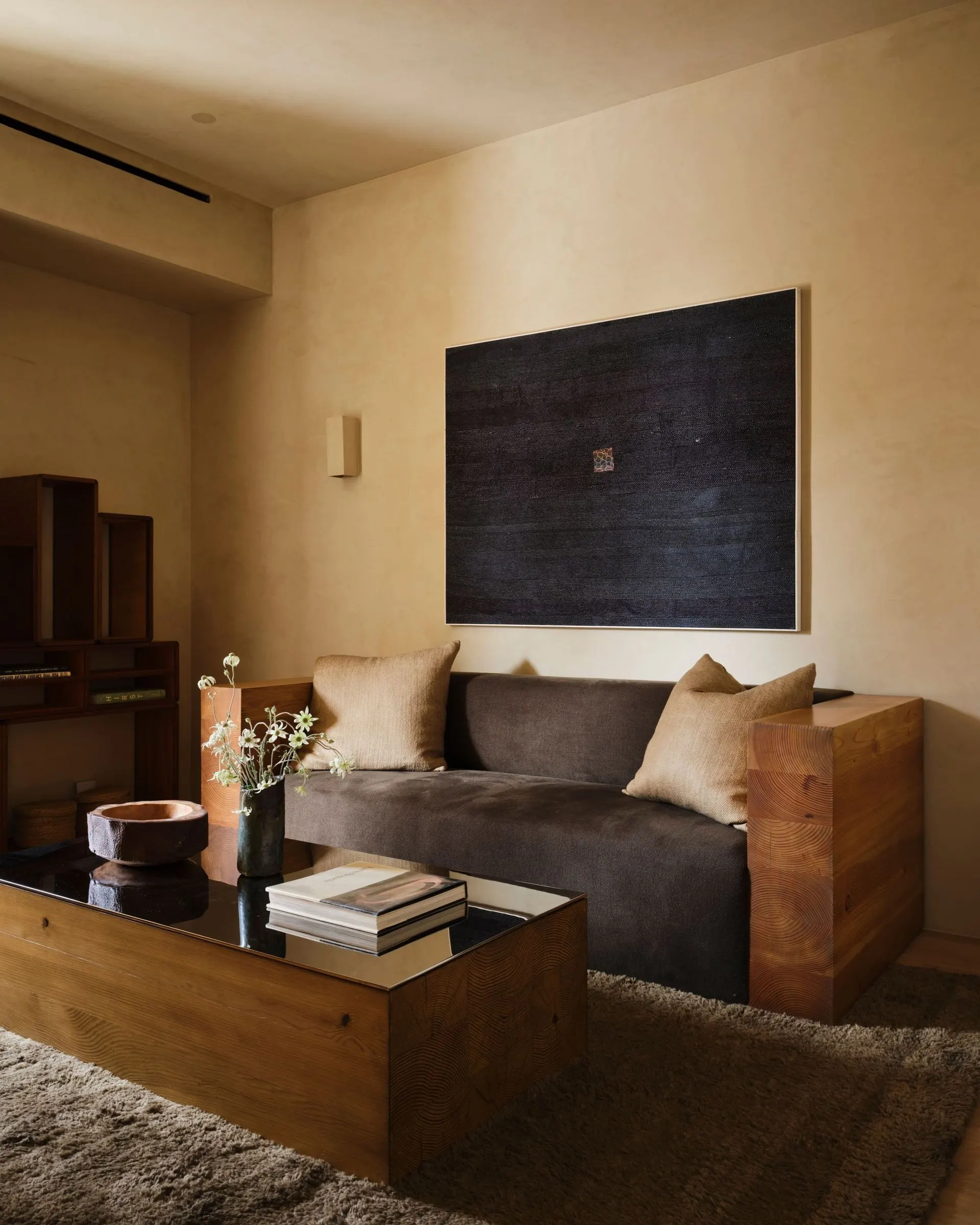 Large dark textured painting with a small red mark above a gray sofa, artwork by Lawrence Calver