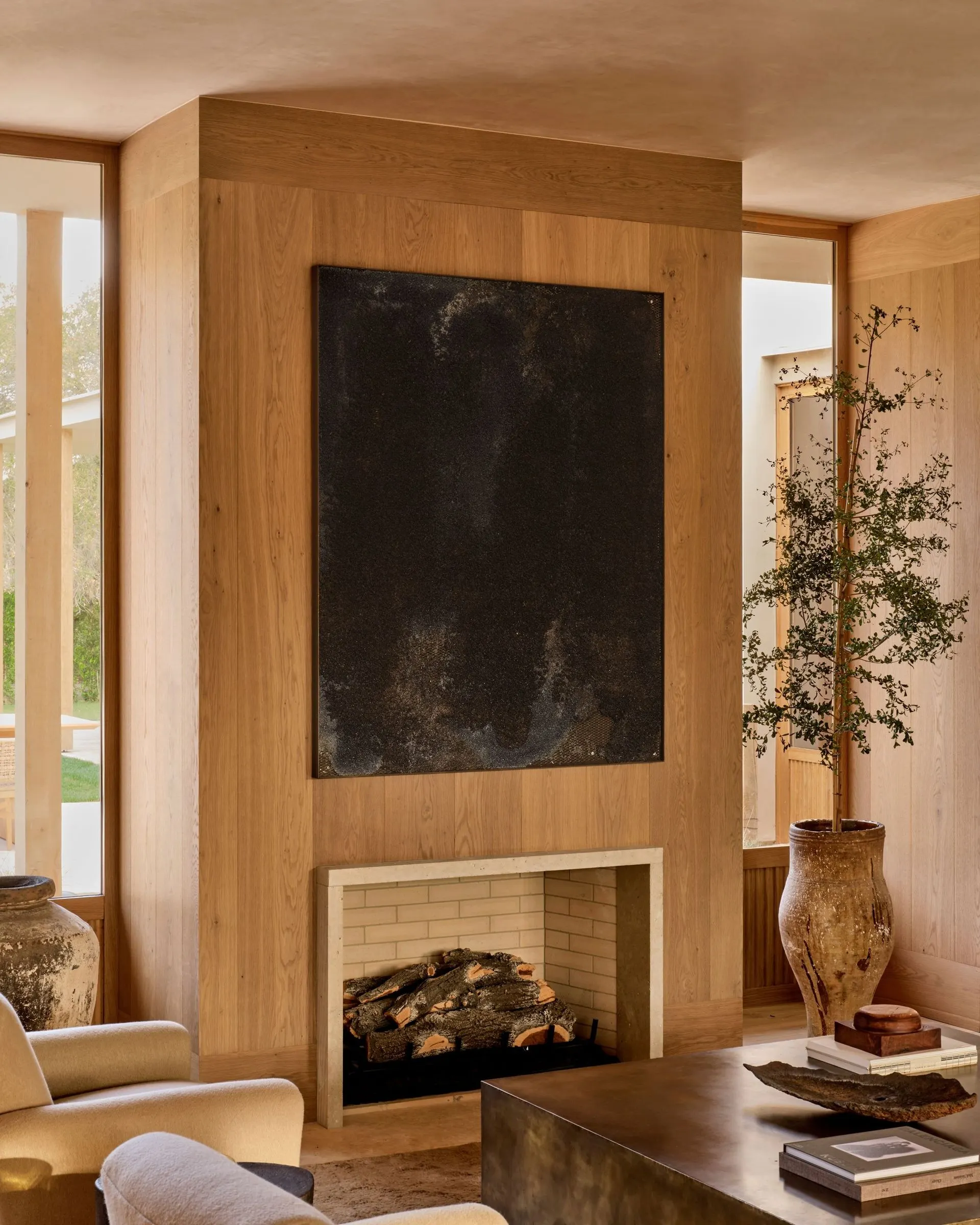 Large black weathered panel artwork above a fireplace on a wood clad wall, artwork by Nick Van Woert