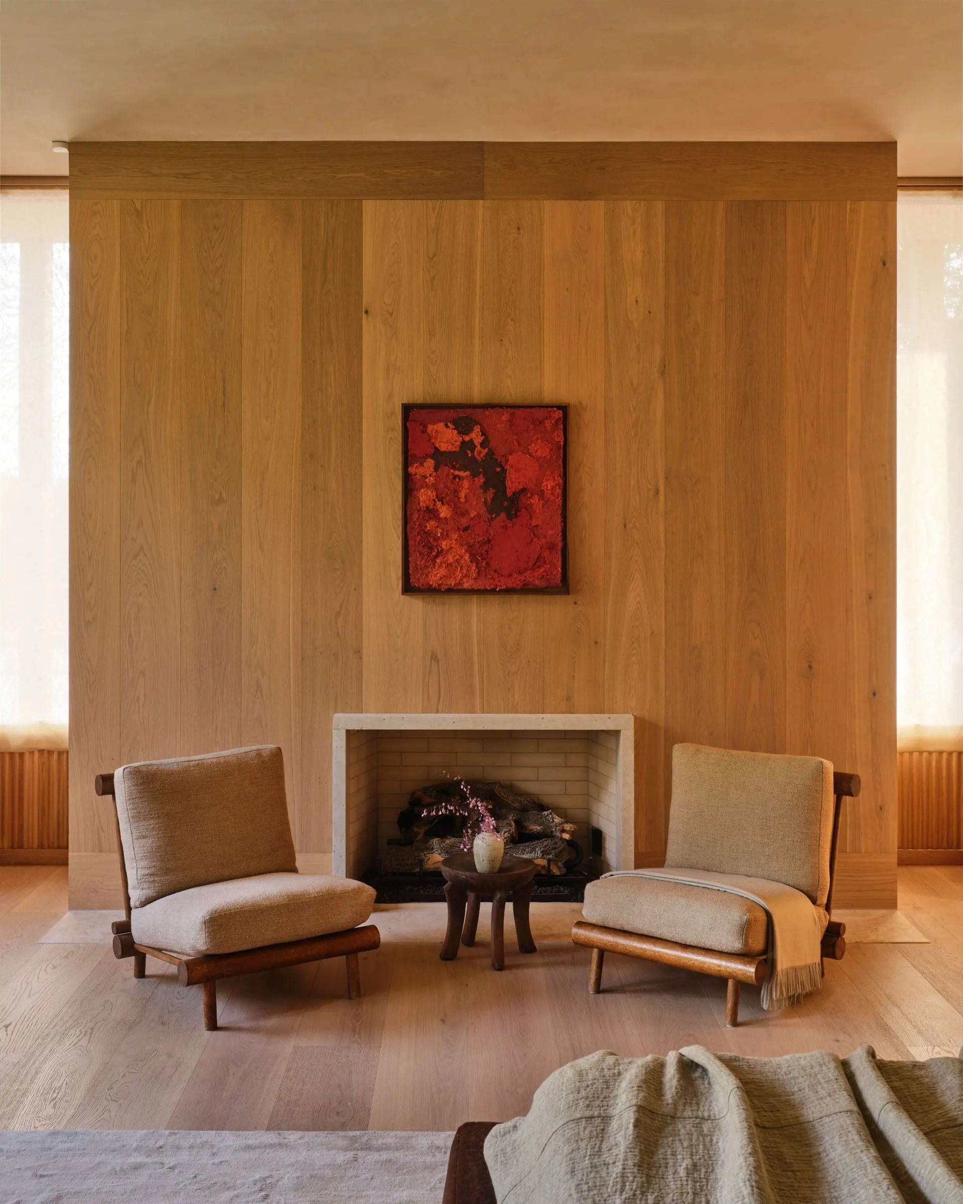 Square red and orange abstract painting above a fireplace in a wood paneled room, artwork by Kour Pour