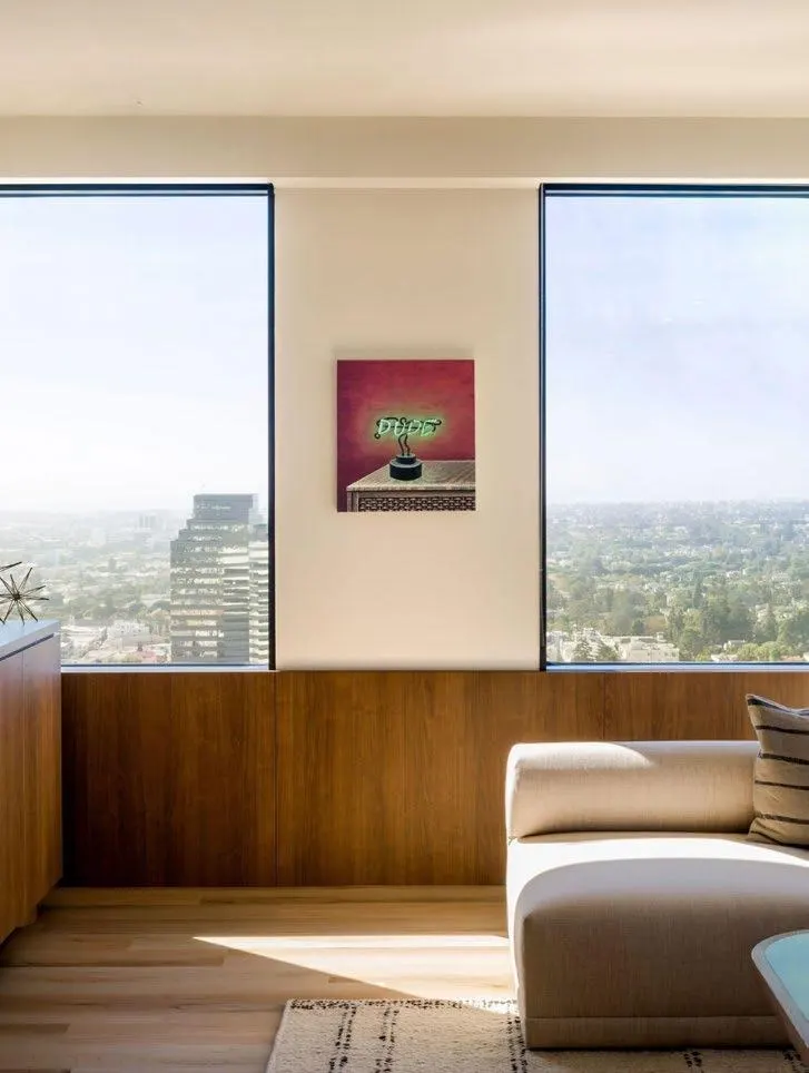 Small red painting of a glowing neon sign between two tall windows with city views, artwork by Joey Wolf