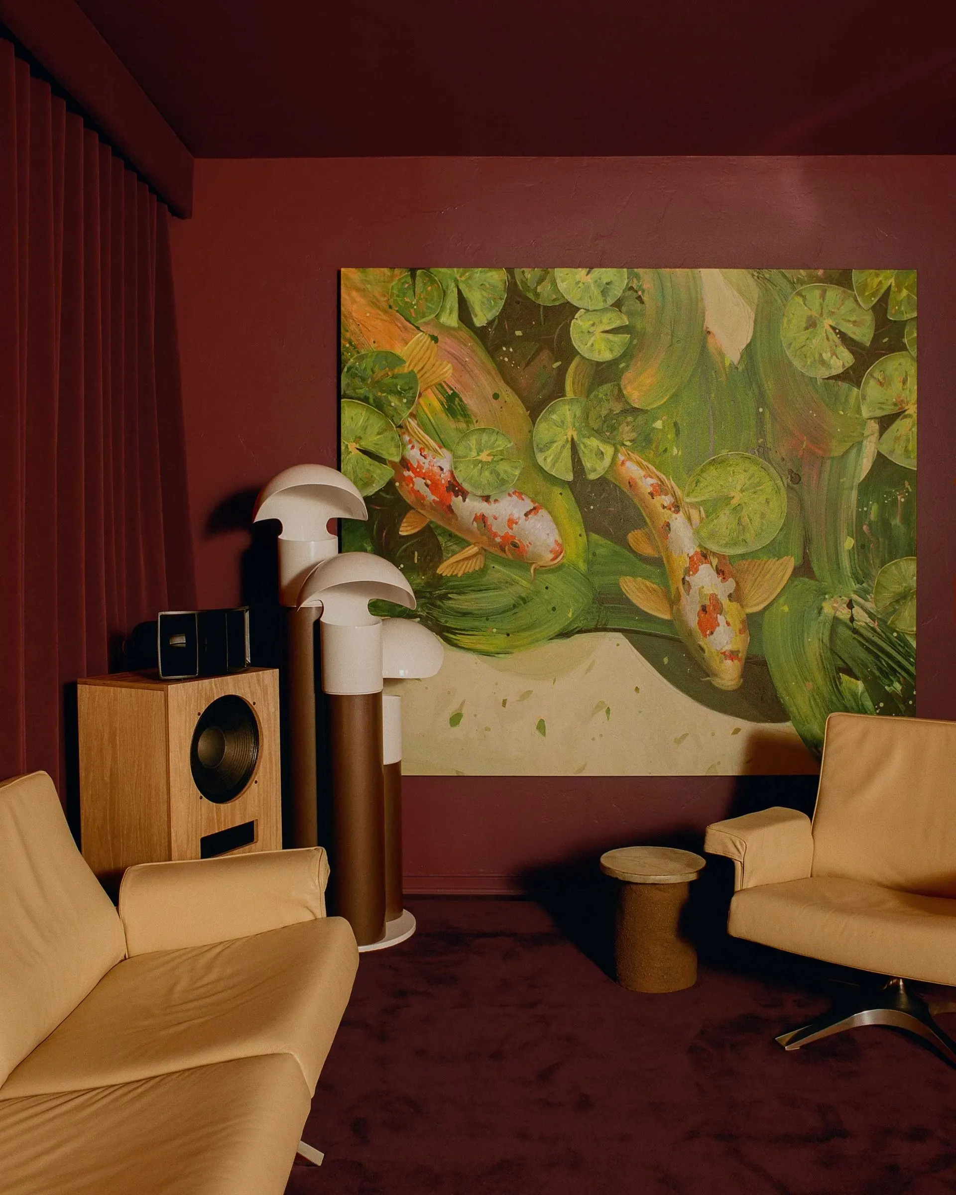 Oxblood media room with a large painting of koi among lily pads above cream leather seating