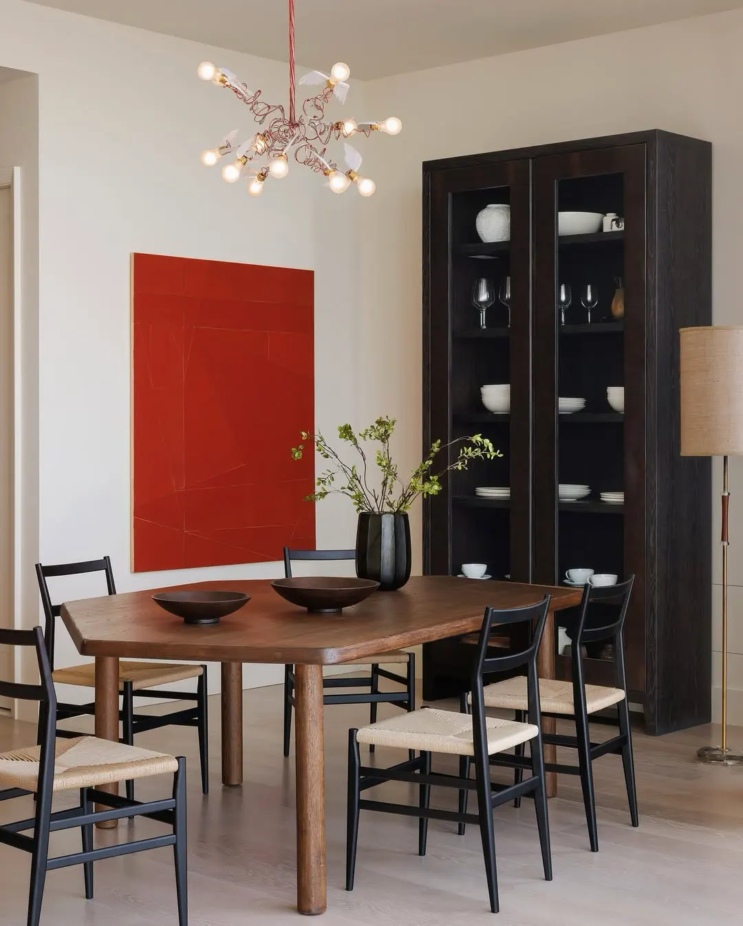 Large red abstract painting beside a dark glass-front cabinet in a dining room, artwork by Florian Schmidt