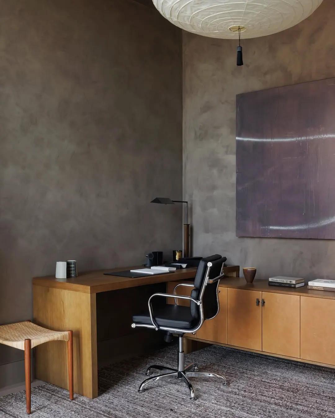 Muted purple abstract painting above a wooden credenza in a home office with a leather chair, artwork by Ramon Enrich
