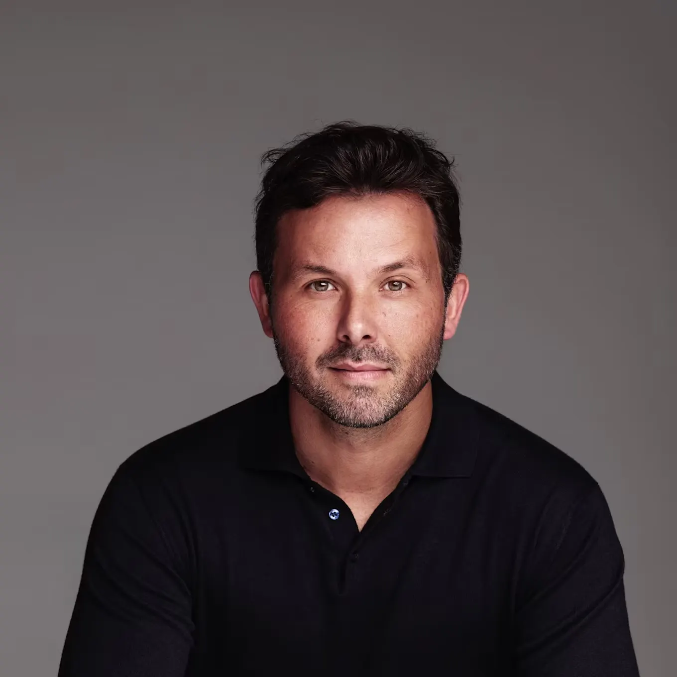 Brian Ludlow, co-founder of Creative Art Partners, in a black knit polo against a gray backdrop