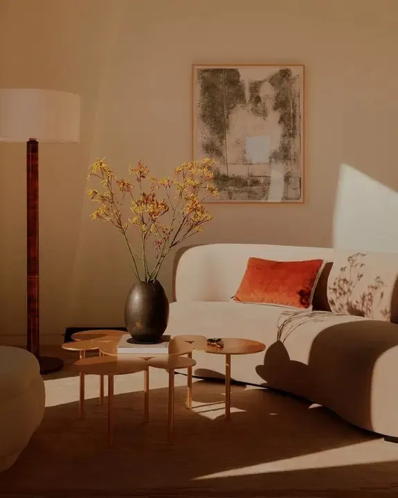 Living room with a white curved sofa, cluster side tables and a framed muted abstract work on paper