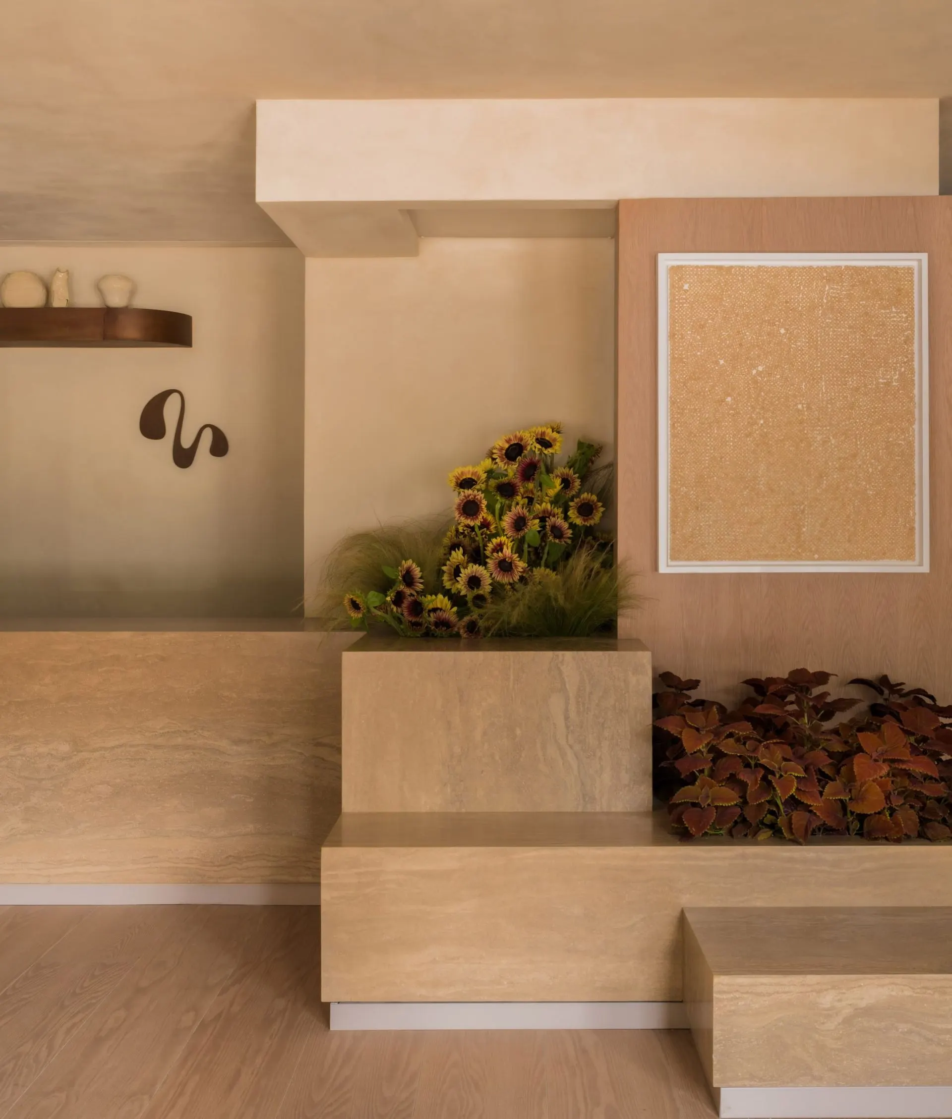 Travertine reception counter with sunflowers, red foliage and a framed textured cork-toned artwork