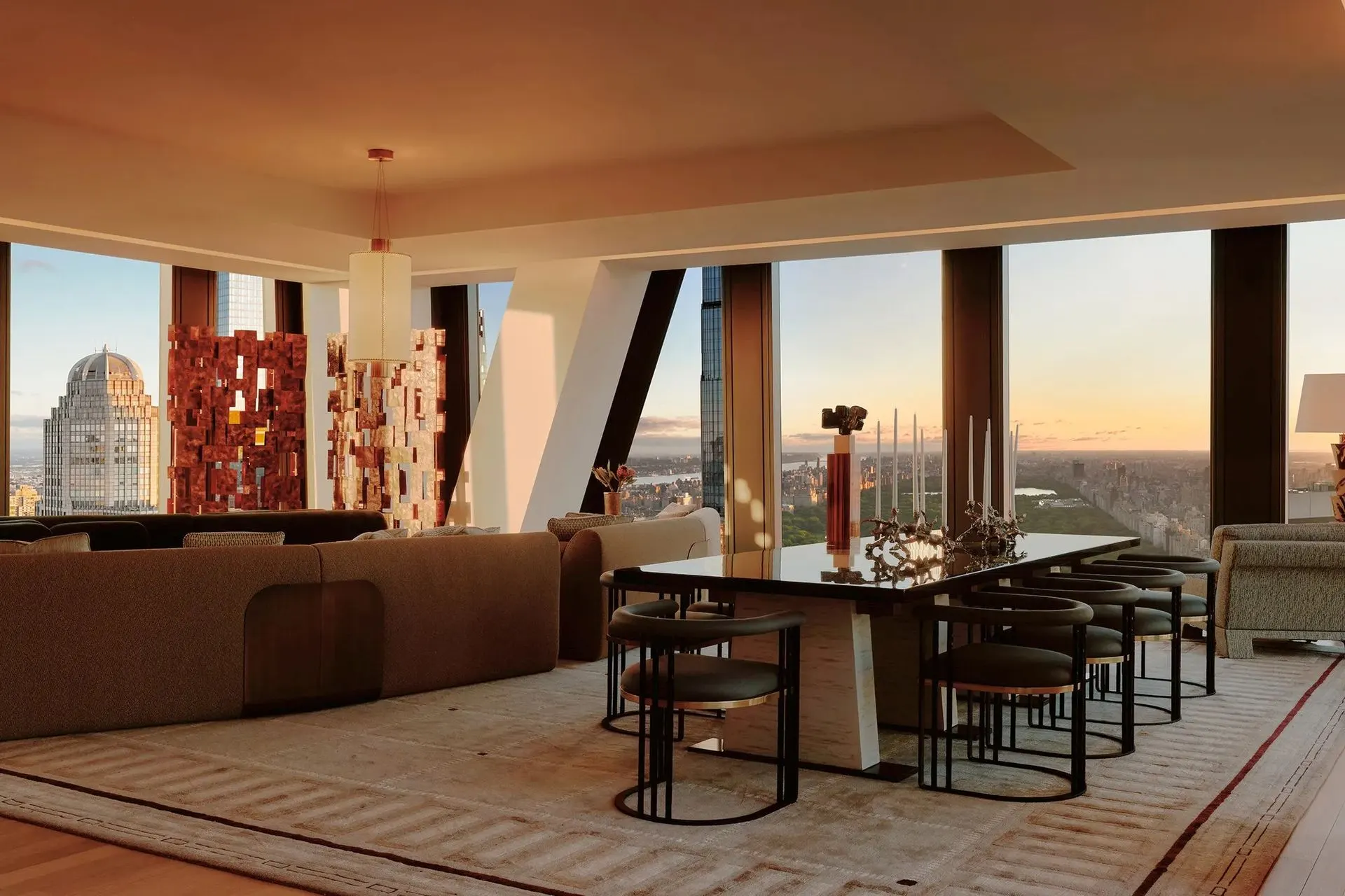 Open living and dining room with bronze relief sculptures, curved sofas and wraparound windows over Central Park