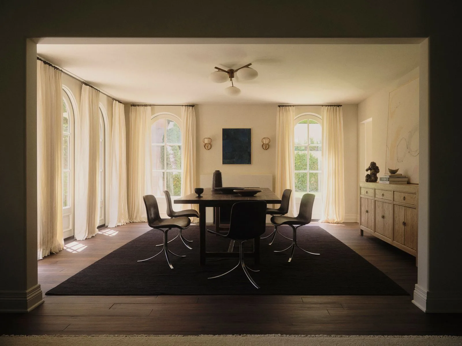 Beverly Hills dining room with arched windows and a small dark blue painting between sconces above a long table