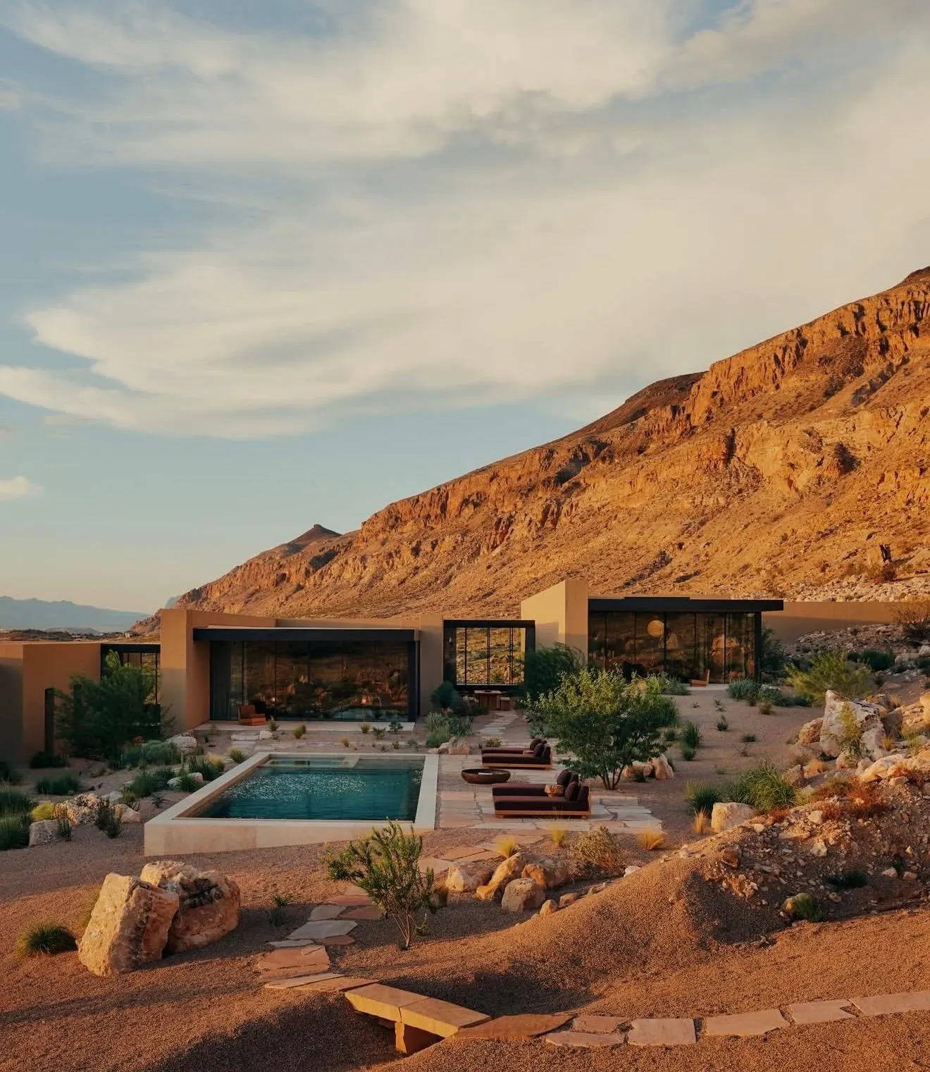 Low desert home with a pool and stone terraces set against red rock mountains at sunset in Utah