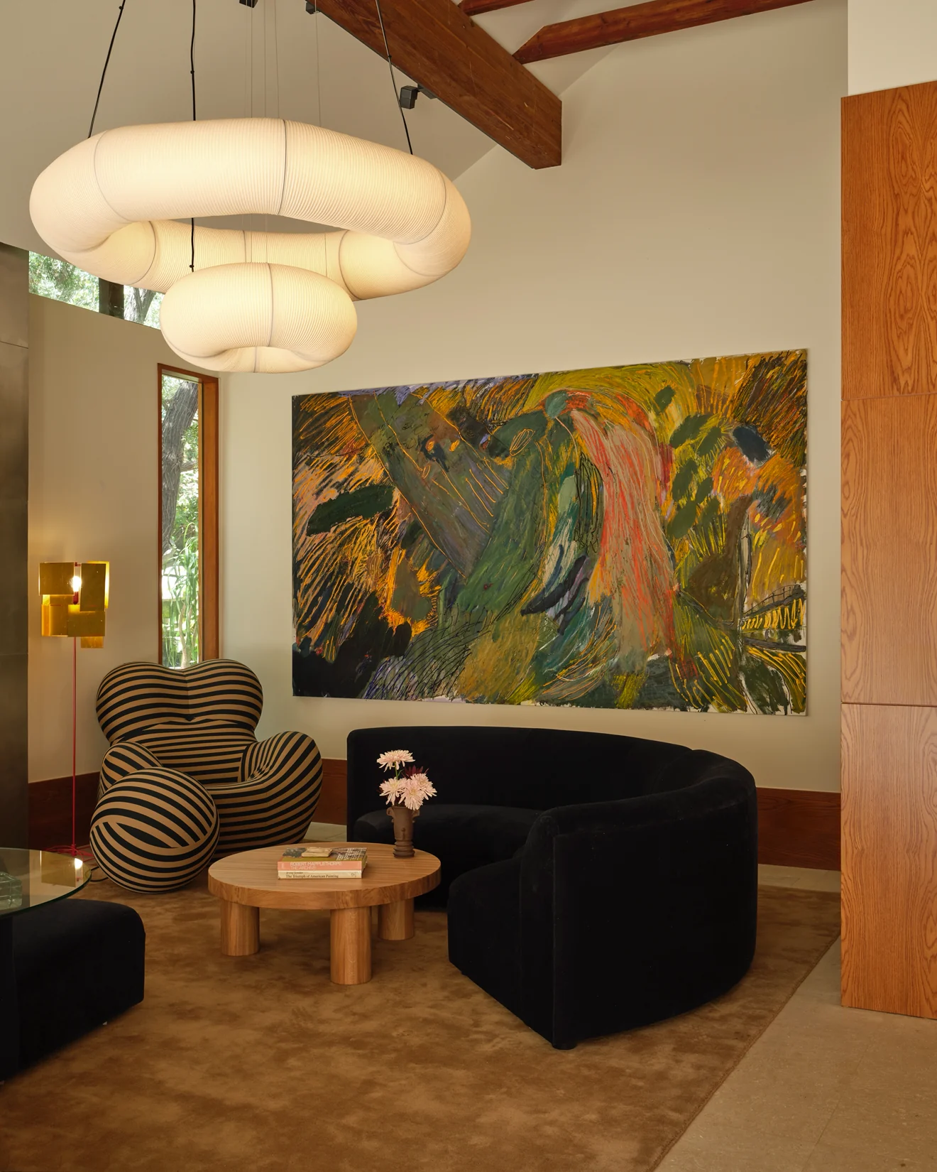 Large abstract painting above a curved black sofa in a designer living room